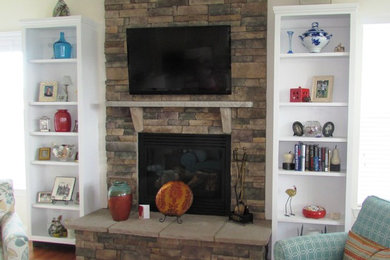 他の地域にある中くらいなトラディショナルスタイルのおしゃれなLDK (白い壁、無垢フローリング、標準型暖炉、石材の暖炉まわり、壁掛け型テレビ、茶色い床) の写真