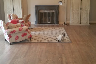 Example of a large classic enclosed light wood floor and brown floor living room design in San Francisco with beige walls, a standard fireplace, a metal fireplace and no tv