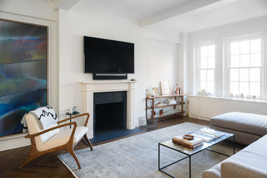 Example of a mid-sized classic medium tone wood floor and brown floor living room design in New York with white walls, a standard fireplace and a wall-mounted tv