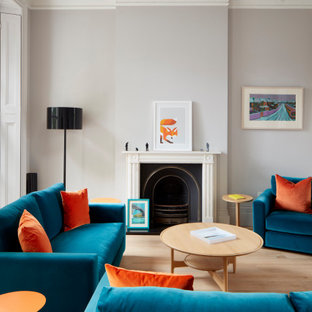 Photo of a large contemporary formal open plan living room in London with grey walls, light hardwood flooring, a standard fireplace, no tv, a stone fireplace surround, brown floors and a vaulted ceiling.