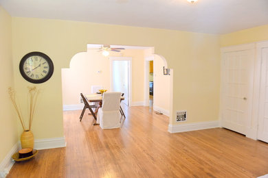 Modelo de salón abierto clásico de tamaño medio sin chimenea con paredes beige y suelo de madera clara