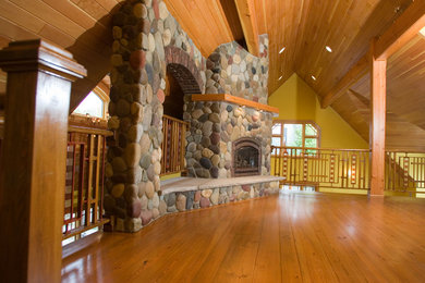 Example of a large mountain style formal and loft-style medium tone wood floor and brown floor living room design in New York with yellow walls, a corner fireplace, a stone fireplace and no tv