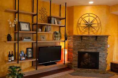 Modelo de salón tradicional de tamaño medio con paredes marrones, suelo de madera clara, chimenea de esquina, marco de chimenea de piedra, televisor independiente y suelo marrón