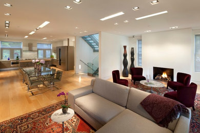 Example of a large trendy formal and open concept light wood floor living room design in Philadelphia with white walls, a standard fireplace and a plaster fireplace