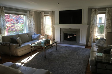 Cette image montre un salon minimaliste avec parquet clair, une cheminée standard, un manteau de cheminée en pierre et un téléviseur dissimulé.