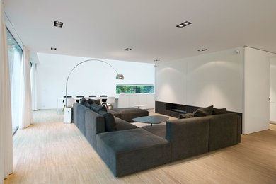 Idée de décoration pour un salon design de taille moyenne et ouvert avec un mur blanc, parquet clair, une cheminée ribbon et un téléviseur dissimulé.