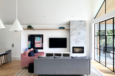 Diseño de salón abierto y abovedado contemporáneo con paredes blancas, suelo de madera clara, todas las chimeneas, televisor colgado en la pared y suelo beige