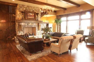 Diseño de salón clásico con suelo de madera en tonos medios, todas las chimeneas y marco de chimenea de piedra
