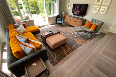 Großes, Repräsentatives, Abgetrenntes Modernes Wohnzimmer ohne Kamin mit grauer Wandfarbe, braunem Holzboden, TV-Wand und grauem Boden in London