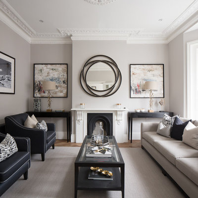 Transitional formal medium tone wood floor living room photo in London with gray walls, a standard fireplace and no tv