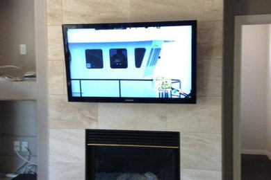 Imagen de salón cerrado contemporáneo de tamaño medio con televisor colgado en la pared, paredes marrones, suelo de baldosas de cerámica, chimeneas suspendidas, marco de chimenea de piedra y suelo beige