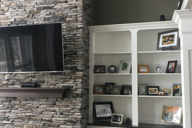 Mid-sized transitional open concept dark wood floor and brown floor living room photo in Other with gray walls, a standard fireplace, a stone fireplace and a wall-mounted tv