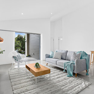 This is an example of a beach style living room in Other with white walls, a freestanding tv and grey floor.
