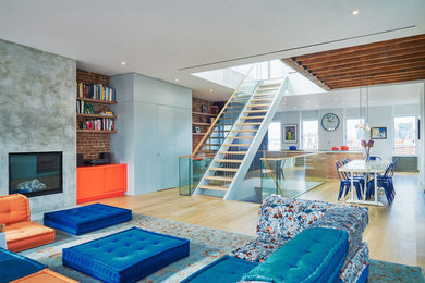Offenes Modernes Wohnzimmer mit hellem Holzboden, Kamin, Kaminumrandung aus Beton und braunem Boden in New York