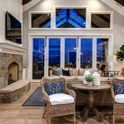 Example of a large farmhouse open concept medium tone wood floor living room design in Salt Lake City with white walls, a standard fireplace, a stone fireplace and a wall-mounted tv