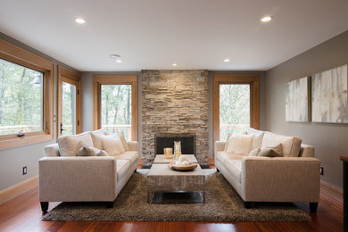 Example of a transitional open concept medium tone wood floor and brown floor living room design in Seattle with gray walls and a stone fireplace