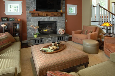 シアトルにある中くらいなトラディショナルスタイルのおしゃれなリビング (オレンジの壁、濃色無垢フローリング、標準型暖炉、石材の暖炉まわり、壁掛け型テレビ) の写真
