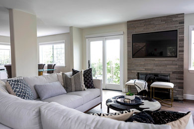 Example of a trendy brown floor living room design in Los Angeles with a standard fireplace, a stone fireplace and a wall-mounted tv