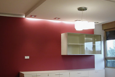 Imagen de salón cerrado actual de tamaño medio con paredes rojas, suelo de madera clara y televisor independiente