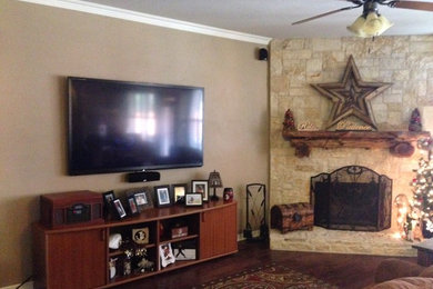 ダラスにあるトラディショナルスタイルのおしゃれなLDK (ベージュの壁、標準型暖炉、石材の暖炉まわり、壁掛け型テレビ、茶色い床) の写真