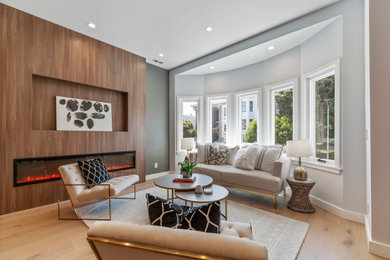 Inspiration for a contemporary light wood floor and beige floor living room remodel in San Francisco with gray walls, a ribbon fireplace and a wood fireplace surround