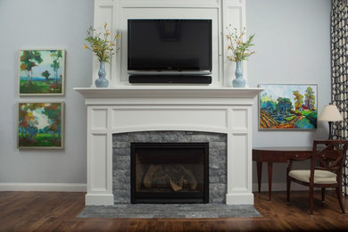 シカゴにあるおしゃれなリビング (白い壁、標準型暖炉、レンガの暖炉まわり、壁掛け型テレビ、茶色い床) の写真