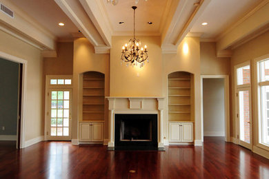 Example of a large classic formal and enclosed dark wood floor living room design in New Orleans with beige walls, a wood stove and a wood fireplace surround