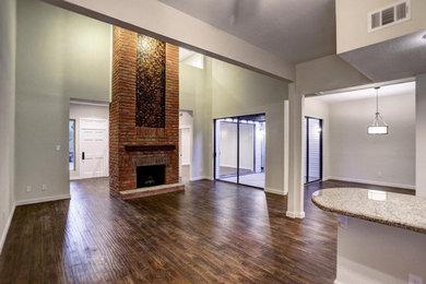 Example of a mid-sized classic open concept dark wood floor and brown floor living room design in Houston with gray walls, a standard fireplace, a brick fireplace and no tv