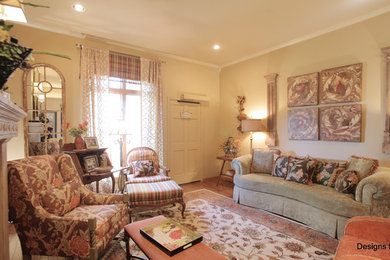 Cette image montre un salon traditionnel de taille moyenne et fermé avec un mur beige, un sol en bois brun, une cheminée double-face, un manteau de cheminée en plâtre et un sol multicolore.
