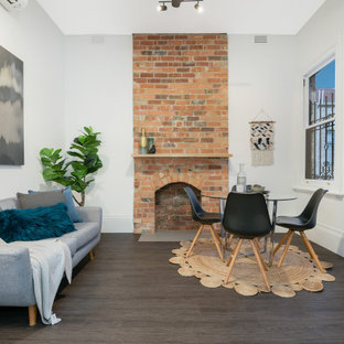 Transitional open concept living room in Melbourne with white walls, dark hardwood floors, a standard fireplace, a brick fireplace surround, no tv and brown floor.