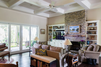 Example of a large beach style open concept dark wood floor living room design in Miami with beige walls, a standard fireplace, a stone fireplace and a media wall