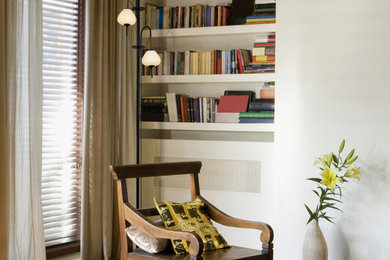 Cette photo montre un grand salon tendance fermé avec une bibliothèque ou un coin lecture, un mur blanc, parquet clair, aucun téléviseur et un sol marron.