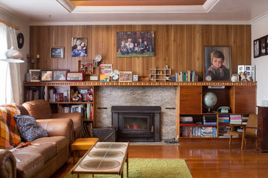 Imagen de salón retro con paredes rojas, suelo de madera en tonos medios, estufa de leña y marco de chimenea de metal