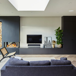 Inspiration for a contemporary open plan living room in Surrey with beige walls, light hardwood flooring, beige floors, a corner fireplace, a plastered fireplace surround and a wall mounted tv.