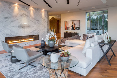 Example of a huge minimalist formal and open concept medium tone wood floor living room design in Los Angeles with white walls, a ribbon fireplace, a stone fireplace and no tv