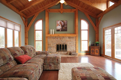 Ejemplo de salón abierto clásico grande con paredes verdes, suelo de madera en tonos medios, todas las chimeneas y marco de chimenea de piedra