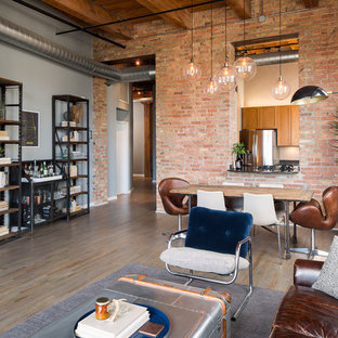 Modelo de salón abierto, industrial, de tamaño medio, con paredes grises, suelo de madera oscura y chimenea tradicional