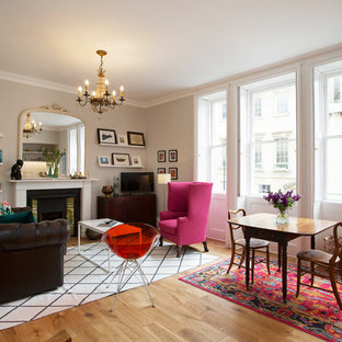 This is an example of a large classic open plan living room in London with light hardwood flooring, a freestanding tv, beige floors, beige walls and a standard fireplace.