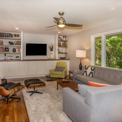 Mid-sized mid-century modern open concept medium tone wood floor and brown floor living room photo in Other with gray walls, a two-sided fireplace and a brick fireplace