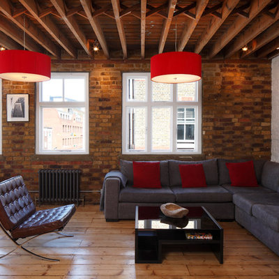 Inspiration for a large industrial open concept light wood floor, brown floor, exposed beam and brick wall living room remodel in London with white walls, no fireplace and no tv