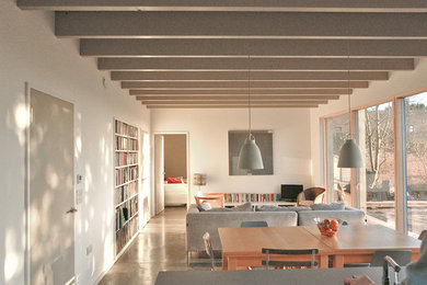 Exemple d'un salon moderne ouvert et de taille moyenne avec un mur blanc, sol en béton ciré, un sol gris et poutres apparentes.