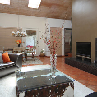 Modelo de salón para visitas abierto, minimalista, grande, con parades naranjas, suelo de baldosas de terracota, todas las chimeneas, marco de chimenea de baldosas y/o azulejos y pared multimedia
