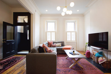 Diseño de salón tradicional renovado con paredes blancas y suelo de madera en tonos medios