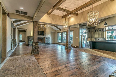 Inspiration for a large rustic open concept medium tone wood floor living room remodel in Houston with beige walls, a standard fireplace, a stone fireplace and a wall-mounted tv