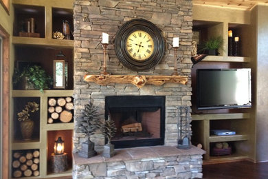 Example of a mid-sized mountain style enclosed medium tone wood floor and brown floor living room design in Phoenix with brown walls, a standard fireplace, a stone fireplace and a wall-mounted tv