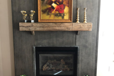 フィラデルフィアにある高級な中くらいなインダストリアルスタイルのおしゃれなリビング (グレーの壁、無垢フローリング、標準型暖炉、金属の暖炉まわり、茶色い床) の写真