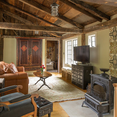 Inspiration for a large cottage medium tone wood floor living room remodel in Boston with green walls, a wood stove and a tv stand