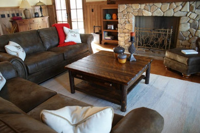 Example of a mid-sized mountain style formal and enclosed dark wood floor and brown floor living room design in Other with yellow walls, a standard fireplace and a stone fireplace