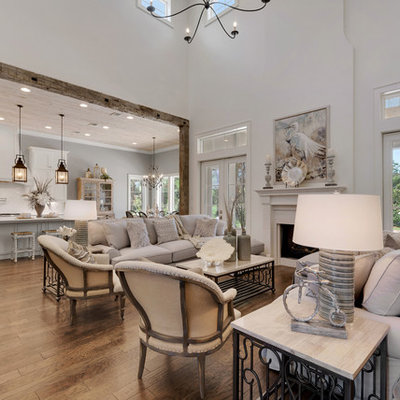 Example of a large cottage formal and open concept medium tone wood floor living room design in Other with white walls, a standard fireplace, a wood fireplace surround and no tv