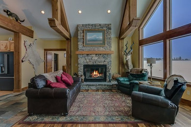 Large mountain style open concept medium tone wood floor and brown floor living room photo in Seattle with beige walls, a standard fireplace, a stone fireplace and no tv